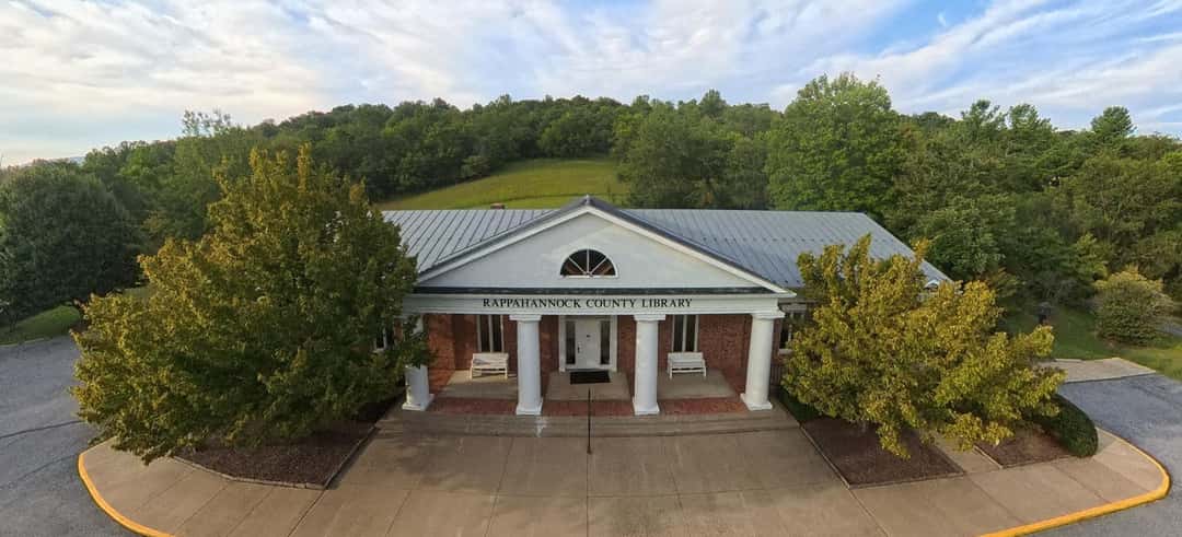 The Rappahannock County Library from the air, centred between two trees with a mown hillside rising behind it.